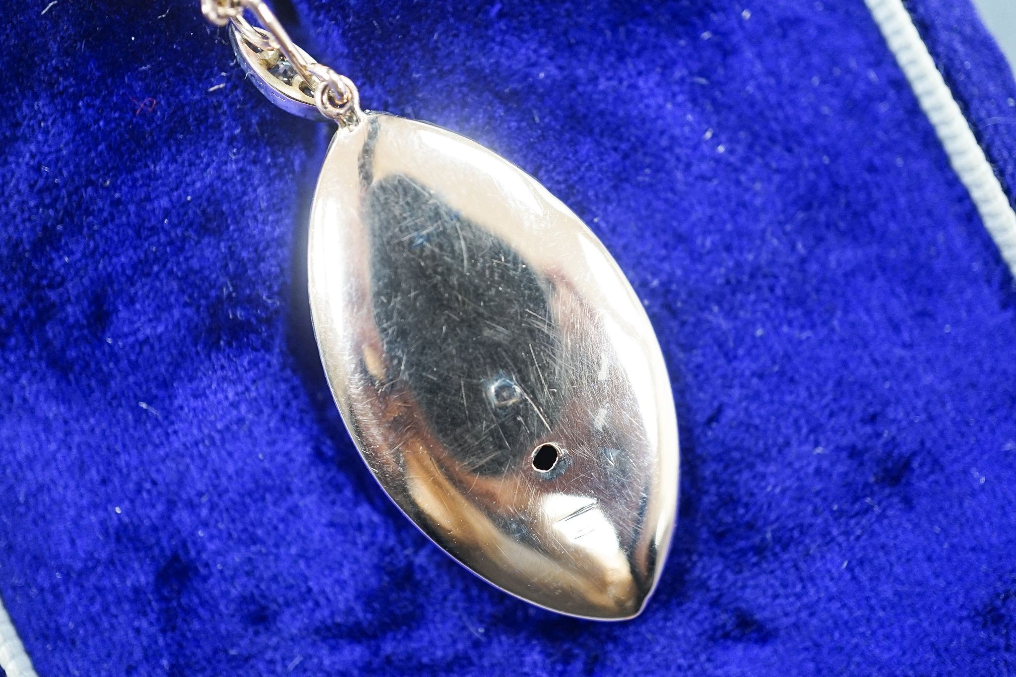 An early 20th century yellow metal, two colour enamel and diamond set navette shaped pendant, 32mm, on a yellow metal chain, 47cm, gross weight 6.9 grams.